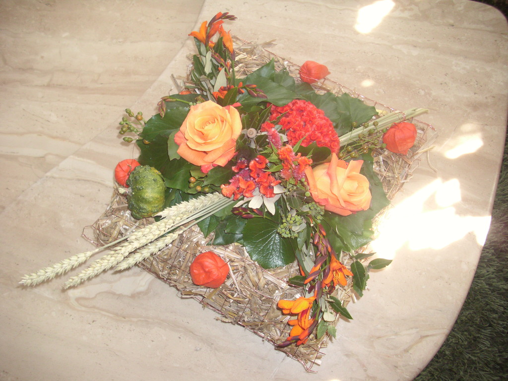Herbstgesteck in einem  Strohpäckli Ären, orange Rosen,Moonpretien,Lampions
